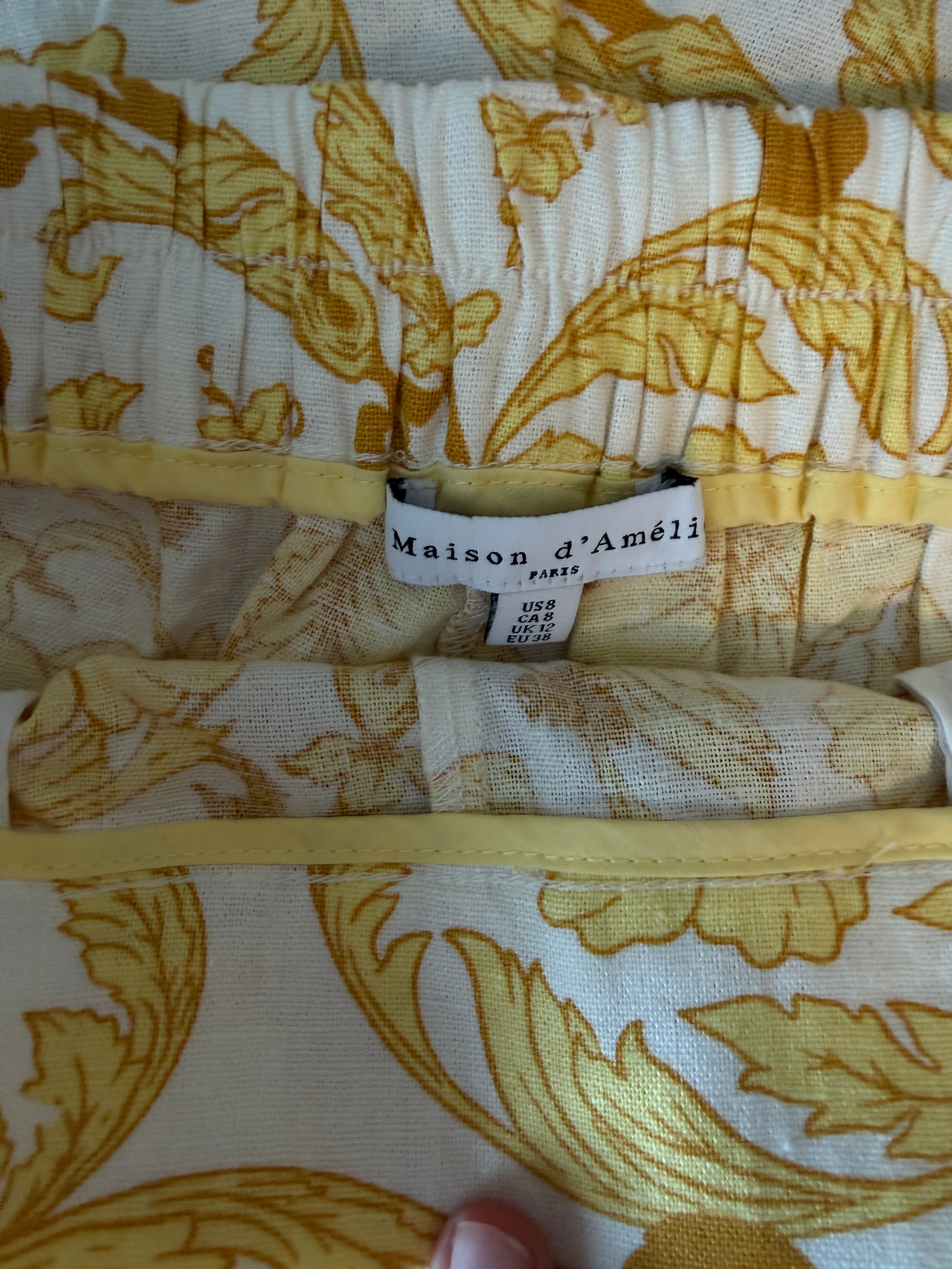 Folded fabric with yellow floral pattern and 'Maison d'Amelie' label.