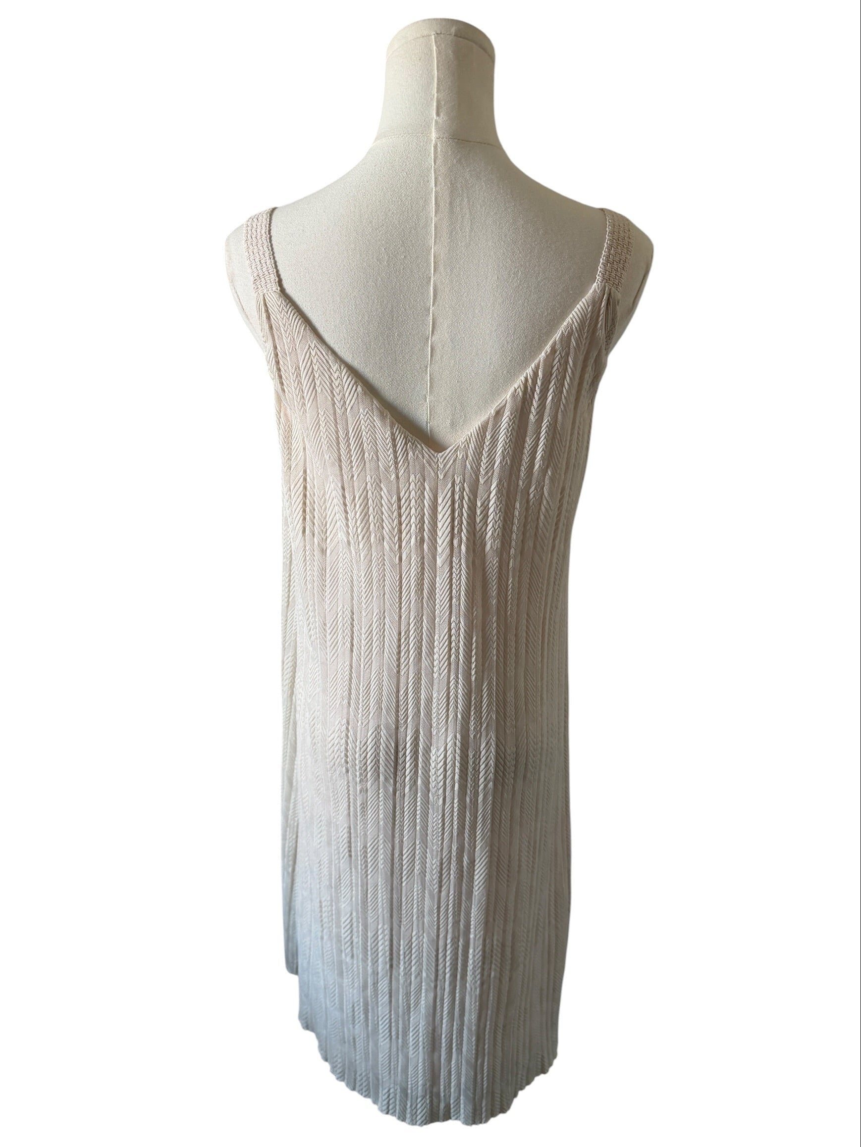 Mannequin wearing a beige and white pleated dress on a white background