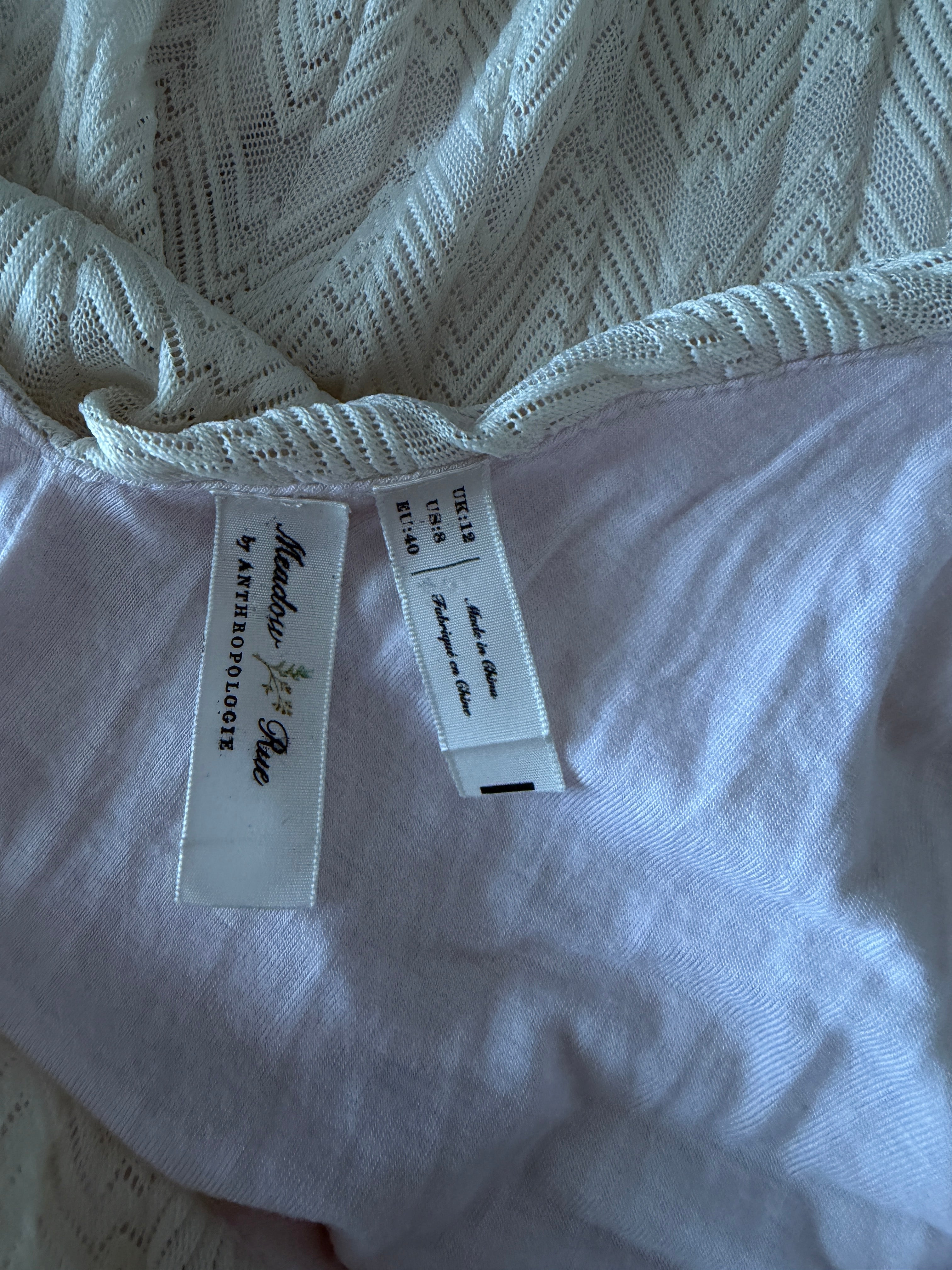 Close-up of a label on a white garment with 'Meadow Rue' branding.