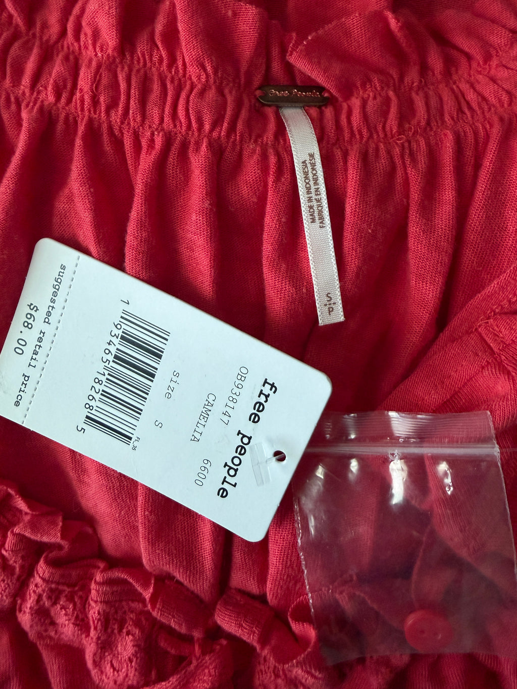 Red garment with a 'free people' tag on a textured red fabric background