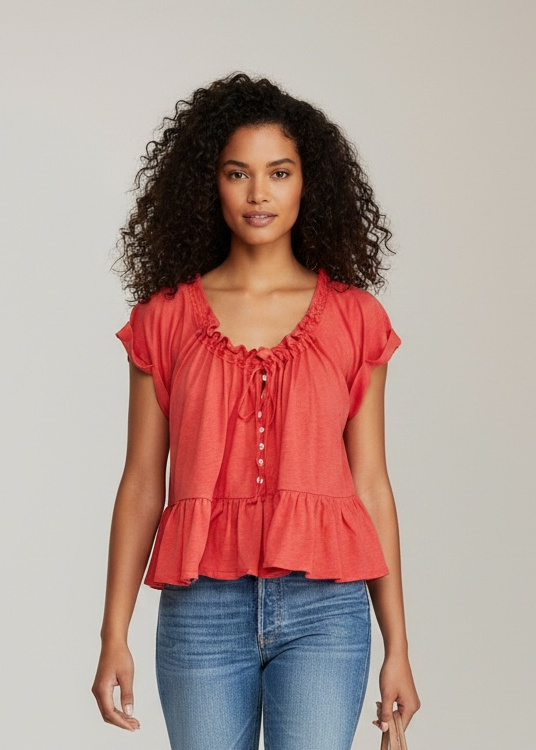 Woman wearing a coral top and blue jeans, holding a beige handbag on a plain background