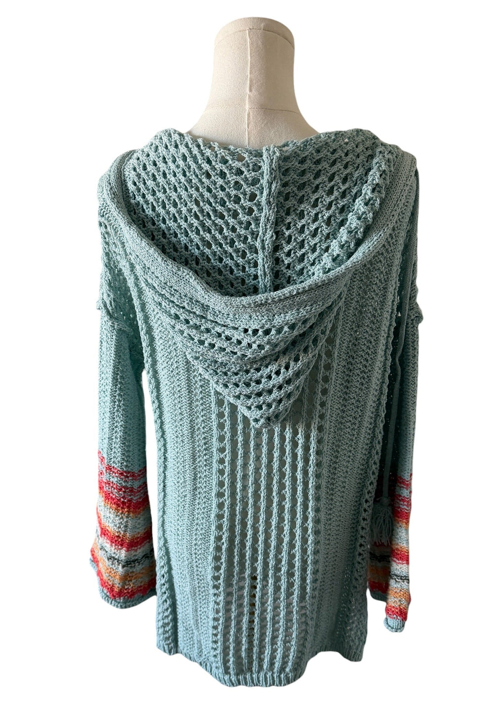 Knitted sweater with colorful cuffs on a mannequin against a white background