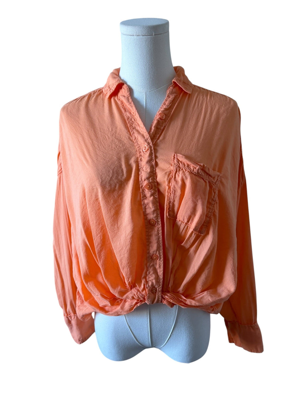 Peach-colored blouse on a mannequin against a white background