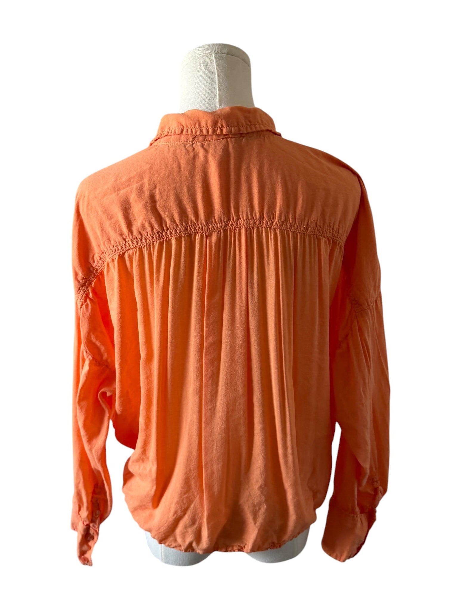 Orange blouse on a mannequin against a white background