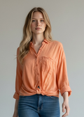 Woman wearing an orange shirt and blue jeans against a plain background