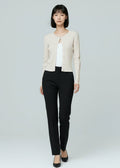 Woman wearing a white cardigan, white top, black pants, and black shoes on a light gray background