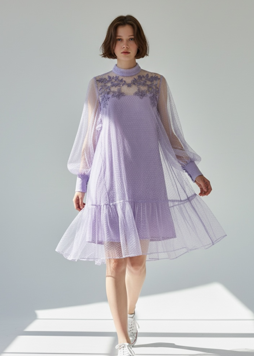 Woman wearing a light purple dress with sheer sleeves on a gray background
