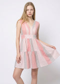 Model wearing a pink and gray dress on a white background