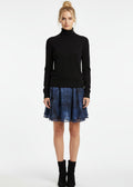 Woman wearing a black turtleneck sweater and blue skirt on a white background