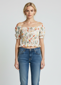 Woman wearing a floral off-shoulder top and blue jeans on a white background