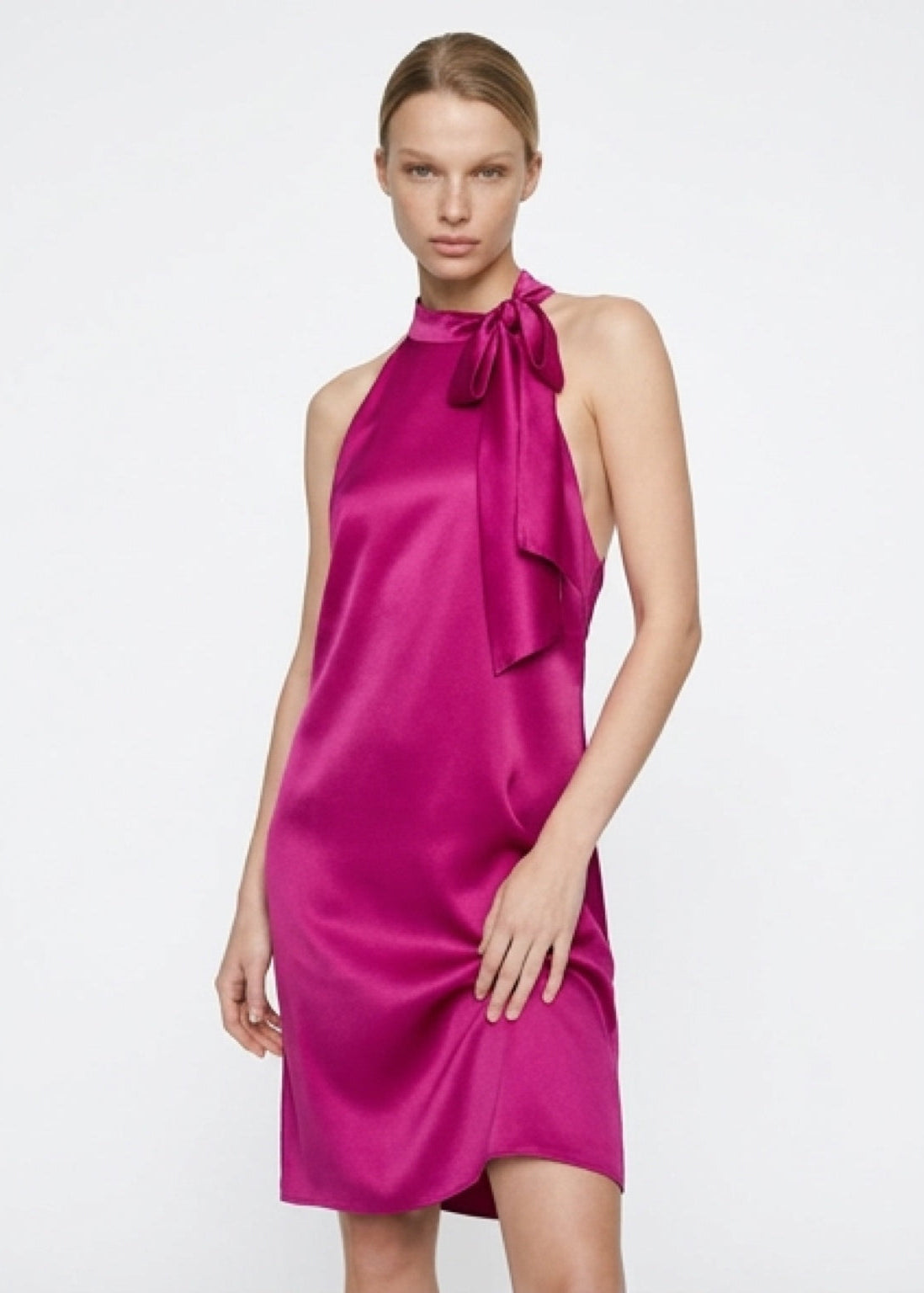 Woman wearing a pink dress with a bow detail on a white background