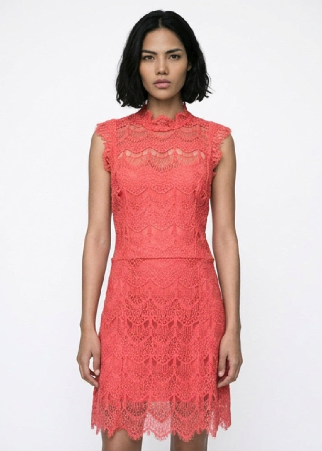 Woman wearing a coral lace dress on a white background