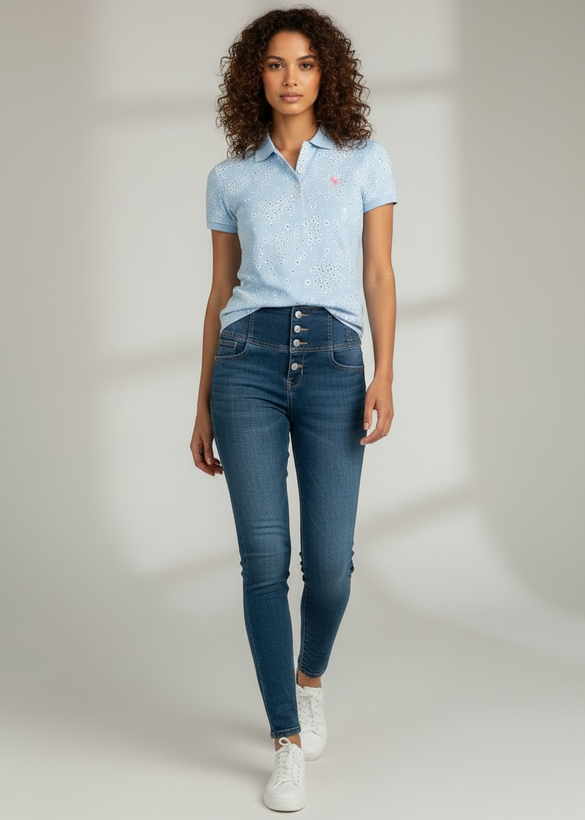 Woman wearing a light blue polo shirt and dark blue jeans on a plain background