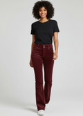 Woman wearing burgundy velvet pants and a black t-shirt on a white background