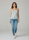 Woman wearing a floral top and blue jeans on a plain background