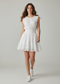 Woman wearing a white dress with lace details on a plain background