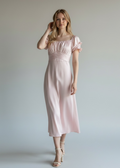 Woman wearing a pink dress against a plain background