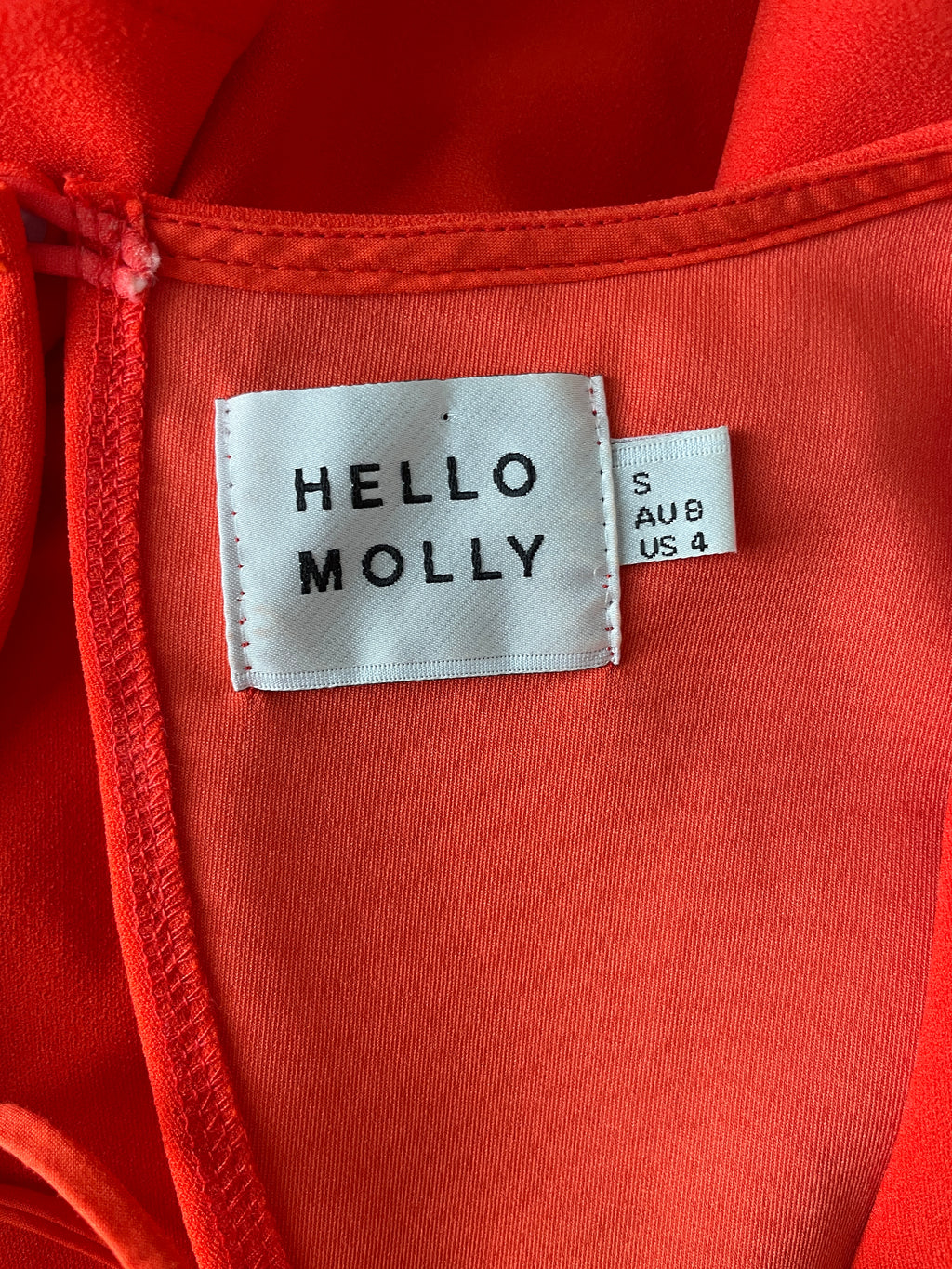 Close-up of a coral garment with 'Hello Molly' label