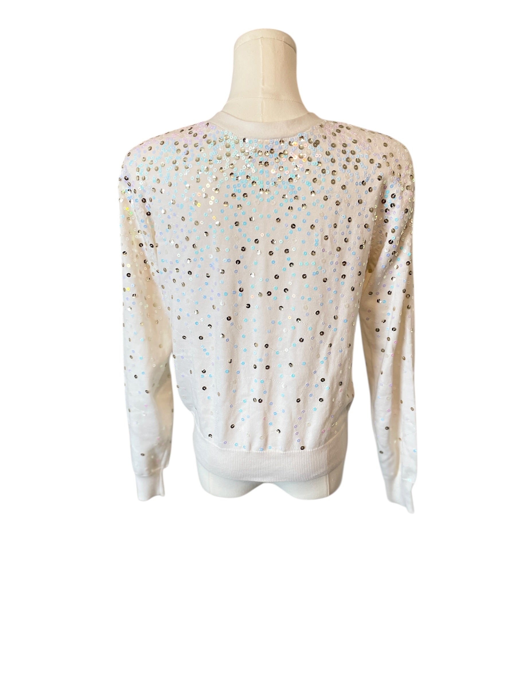 White sweater with black polka dots on a mannequin against a white background