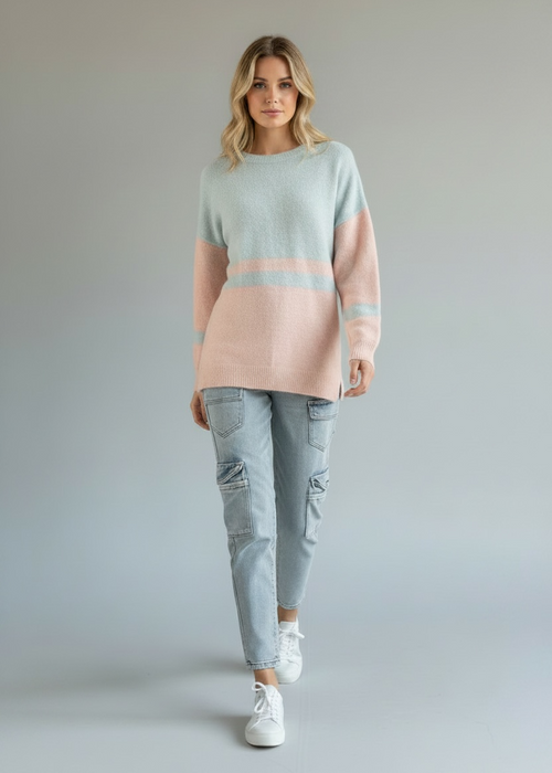 Woman wearing a pastel striped sweater and light blue jeans on a plain background