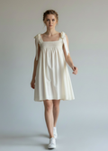 Woman wearing a white dress against a plain background