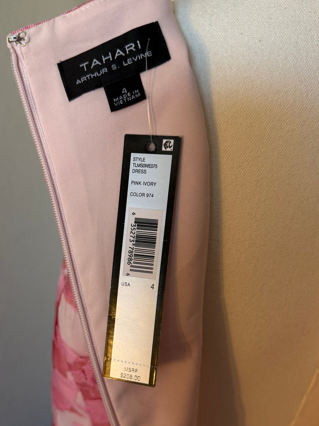 Close-up of a pink garment with brand labels on a neutral background
