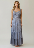 Woman wearing a blue tiered dress against a plain background