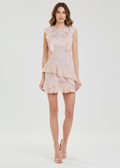 Woman wearing a light pink lace dress on a white background