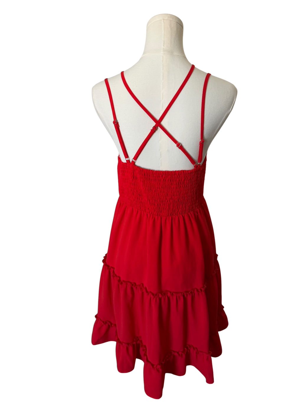 Red dress with criss-cross straps on a mannequin against a white background