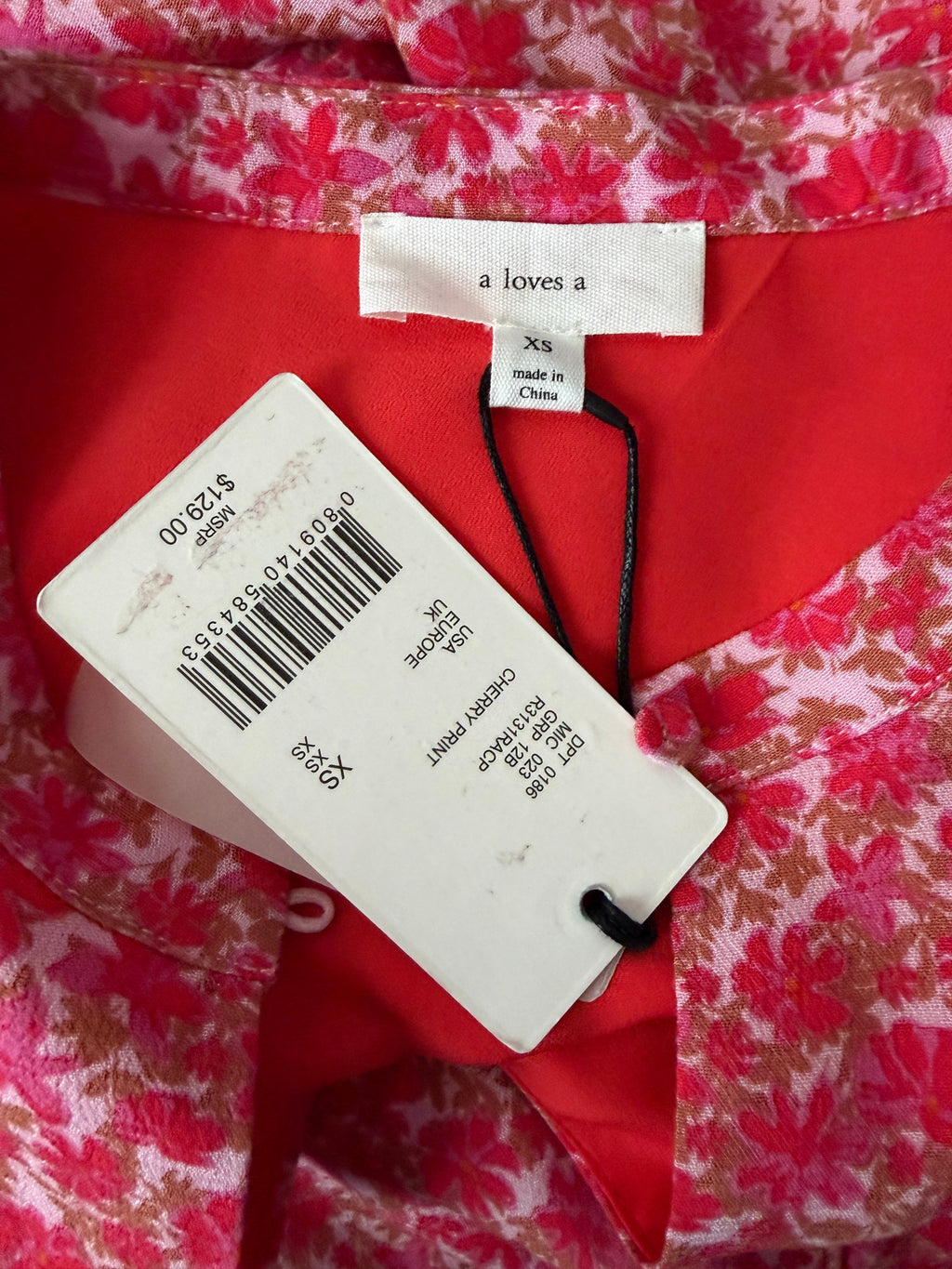 Red floral fabric with a clothing tag and label on a red background