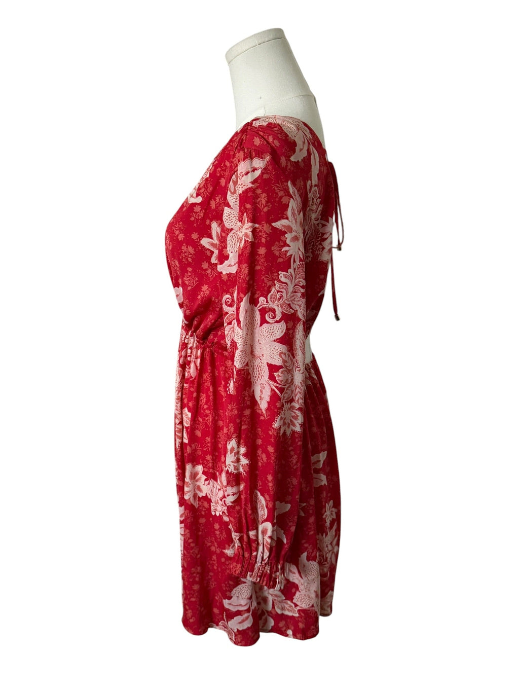 Red dress with white floral pattern on a mannequin against a white background