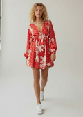 Woman wearing a red floral dress against a white background