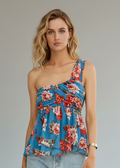 Woman wearing a floral one-shoulder top and denim shorts on a plain background