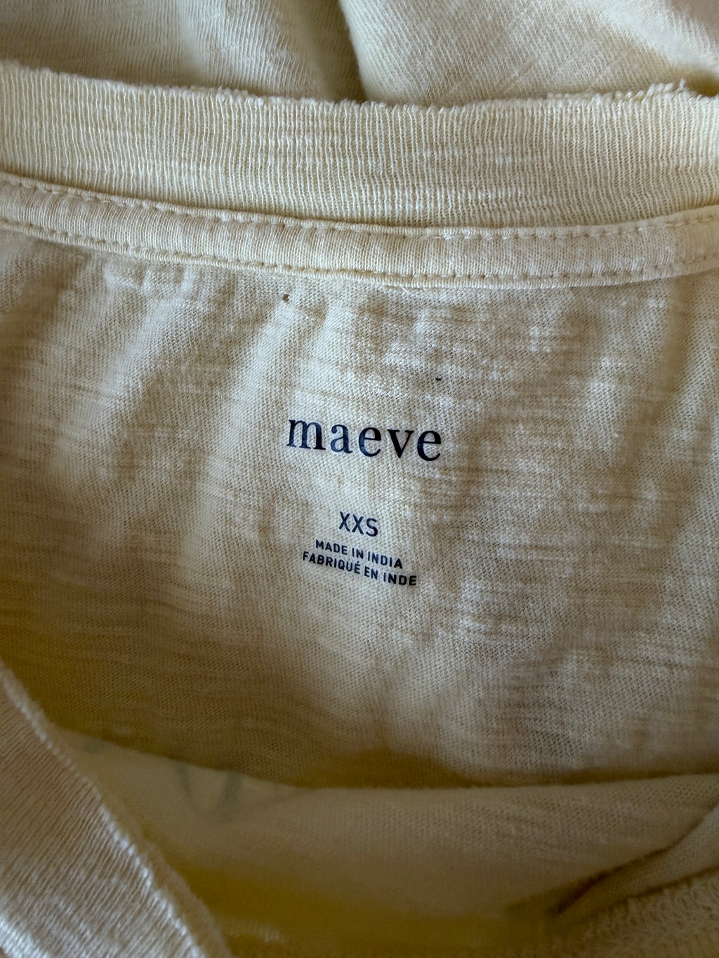 Close-up of beige fabric with 'maéve' label on a plain background