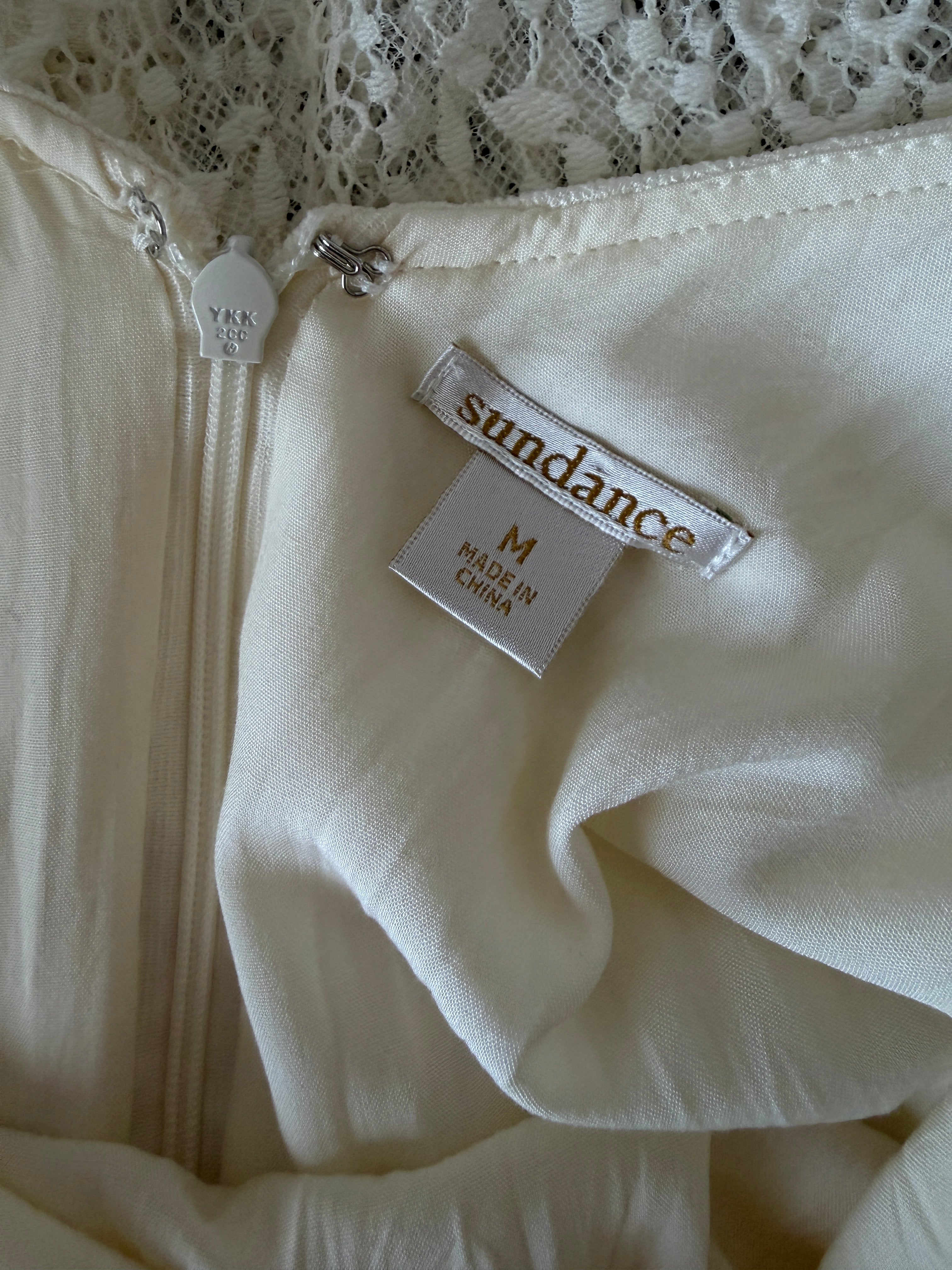 Close-up of a white garment with a 'Sundance' tag on a textured background