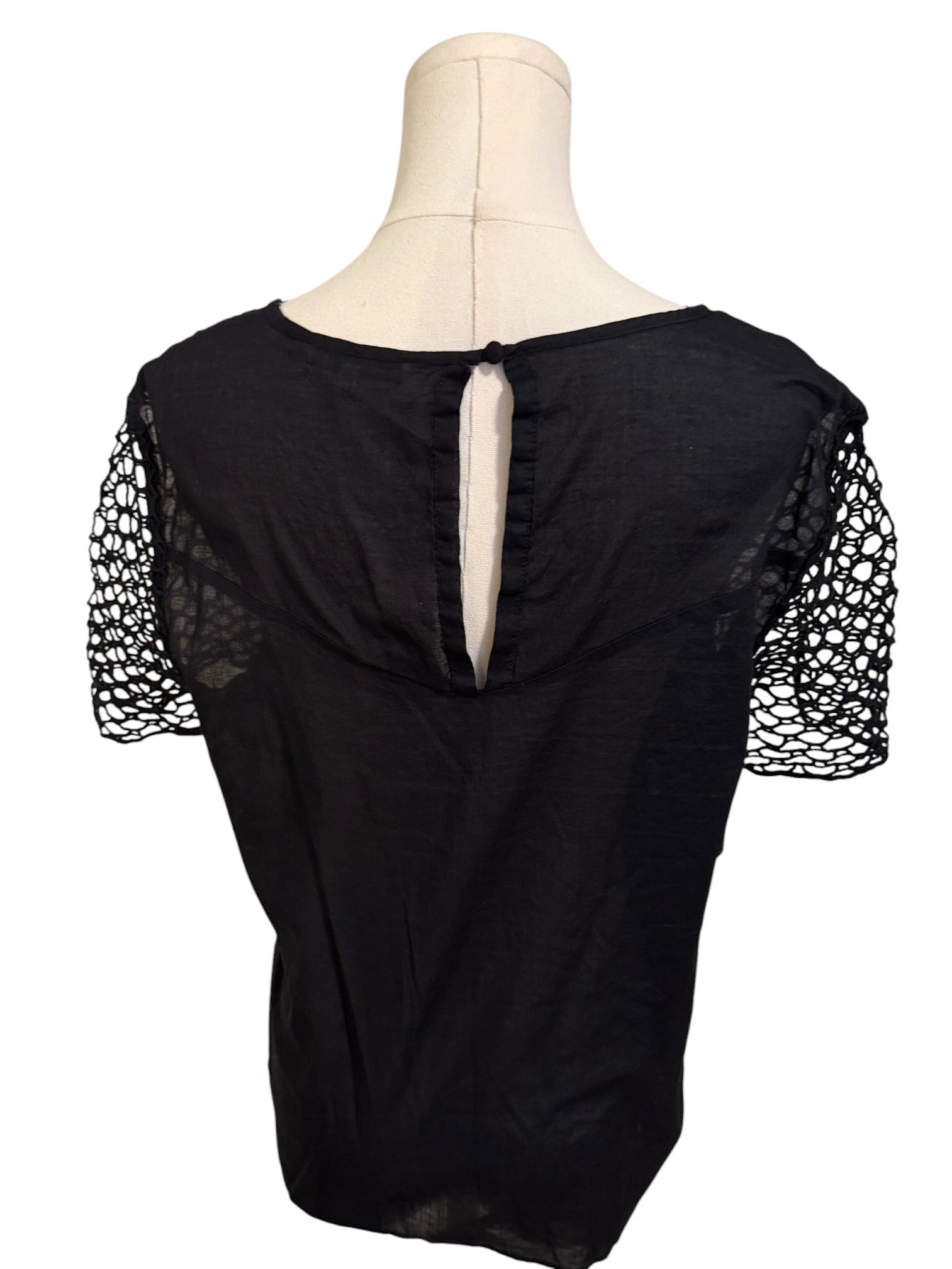 Black top with mesh sleeves on a mannequin against a white background