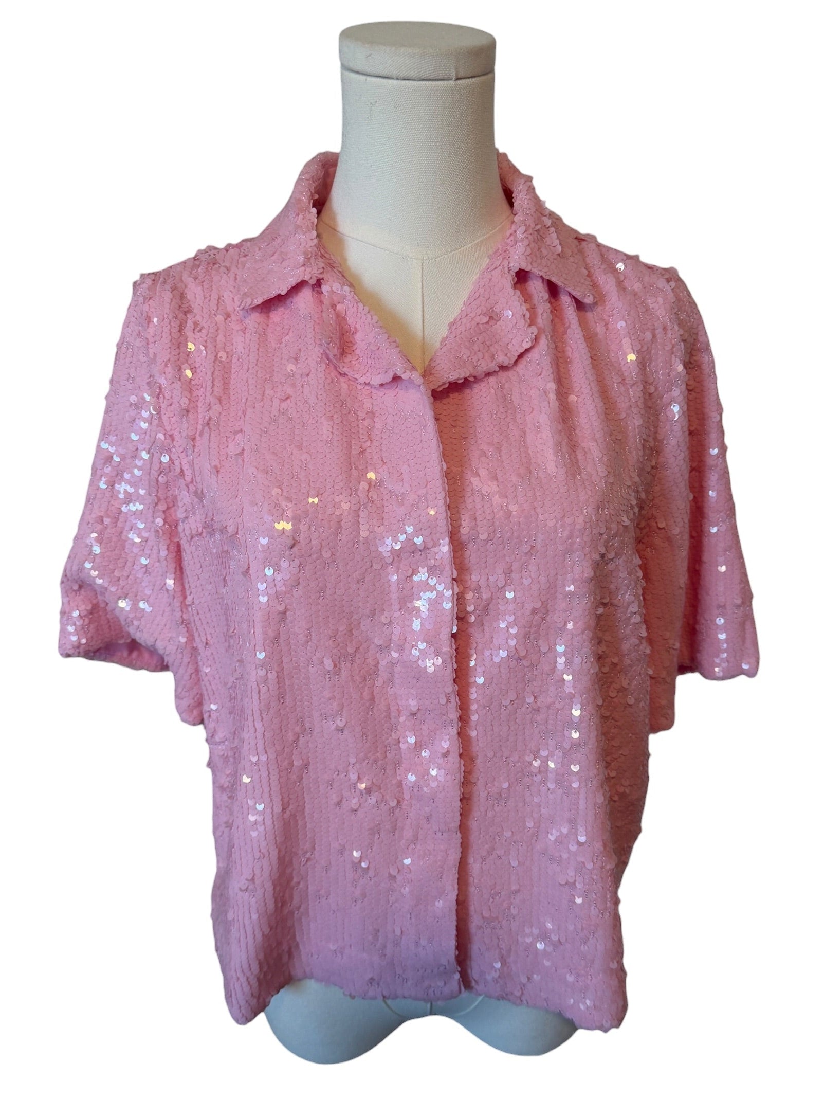 Pink sequin blouse on a mannequin against a white background