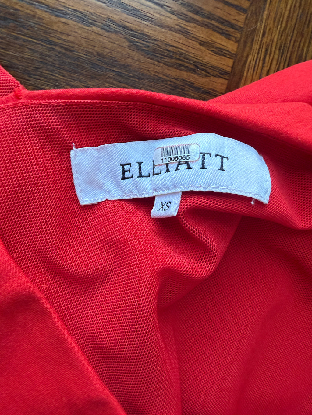 Red garment with 'ELLIATT' label on a wooden surface