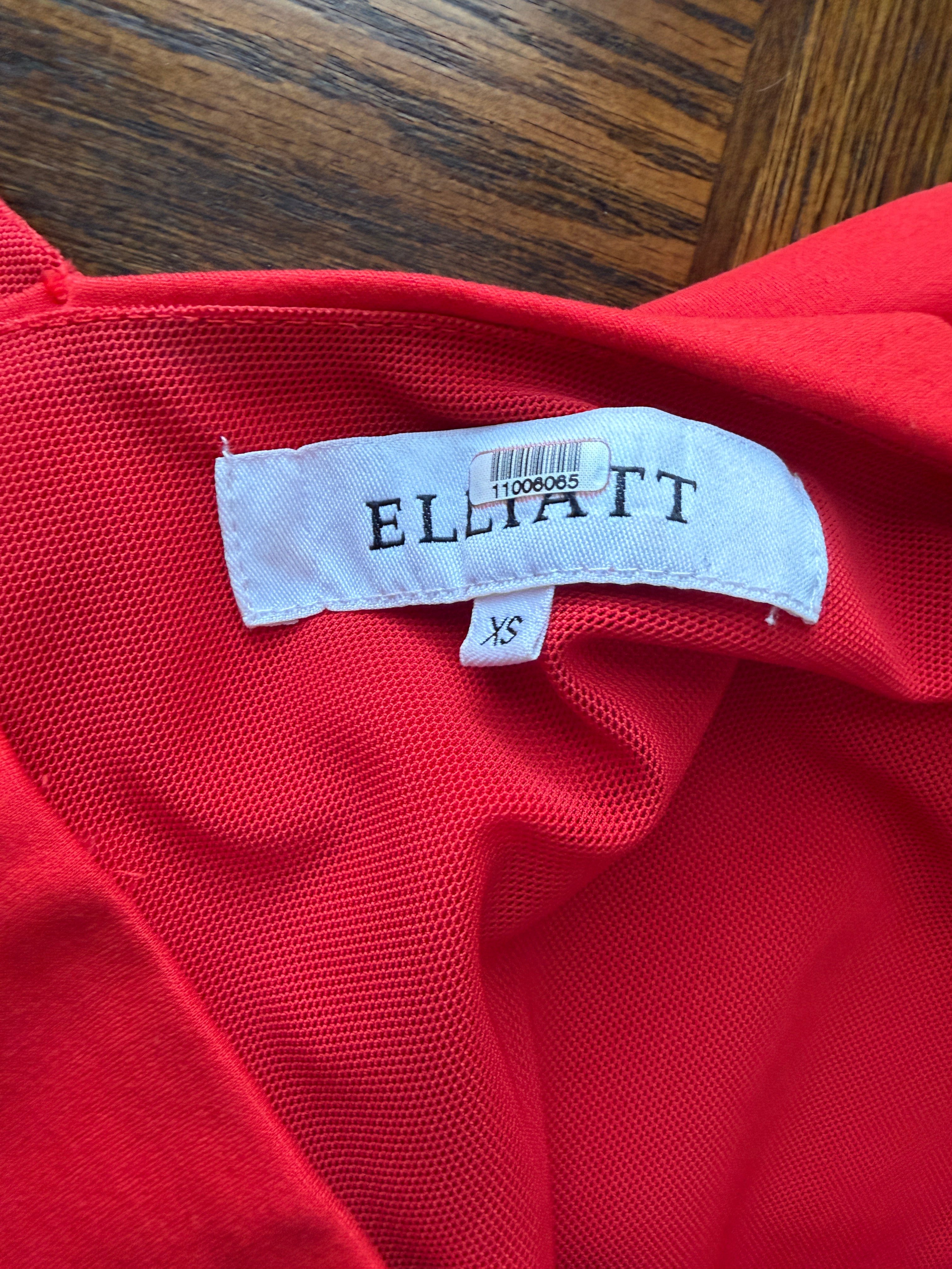 Red garment with 'ELLIATT' label on a wooden surface