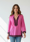 Woman wearing a pink blouse with black trim on a white background